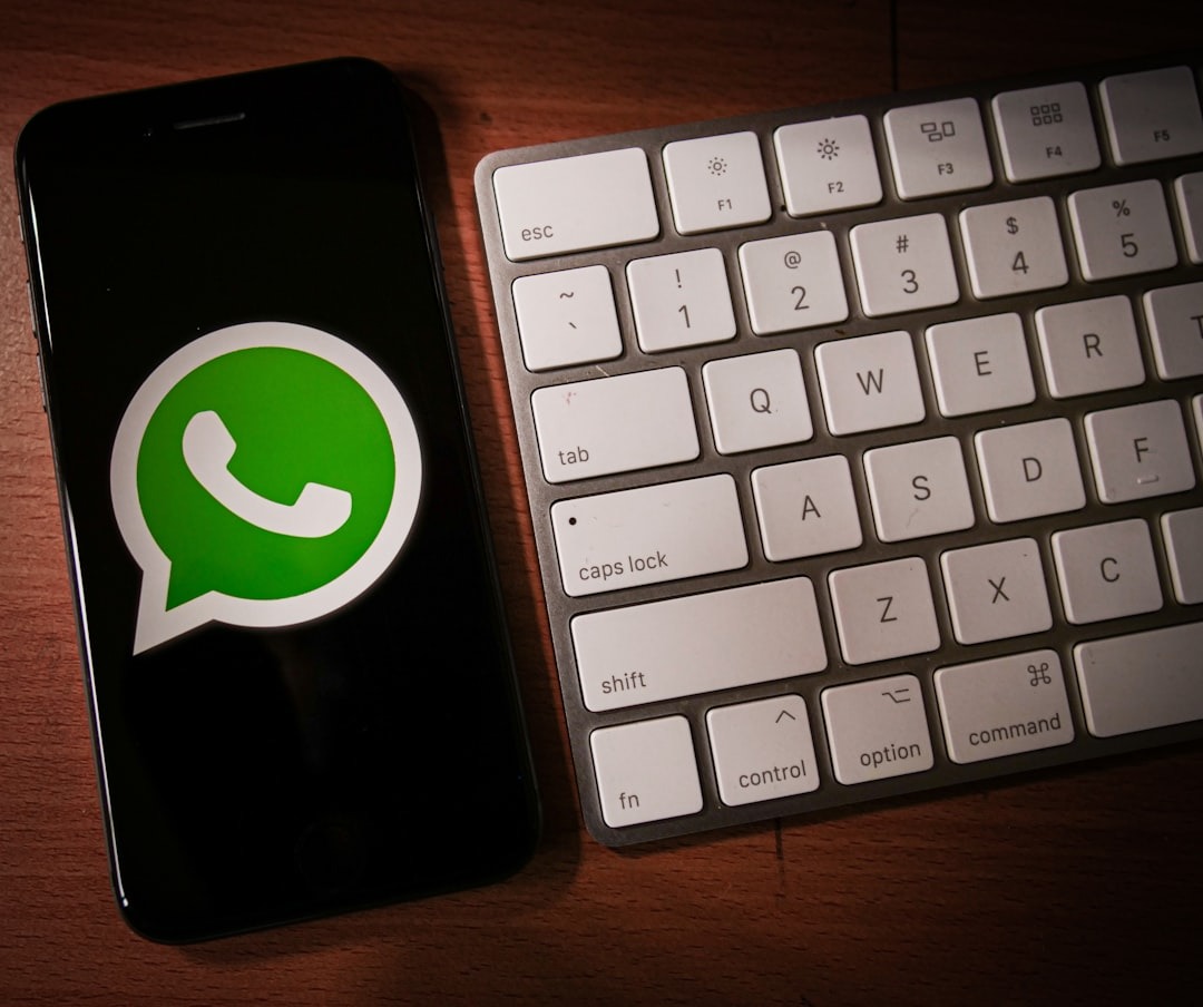 Smartphone screen shows WhatsApp logo next to a computer keyboard.