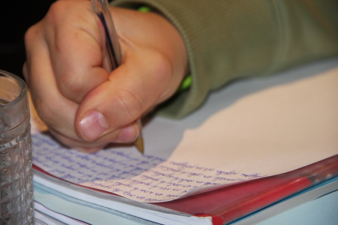 Hand writing with a clear pen on a blue-lined paper.